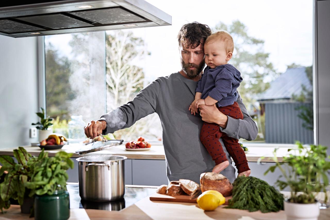 Pappa lagar mat och håller i sin baby