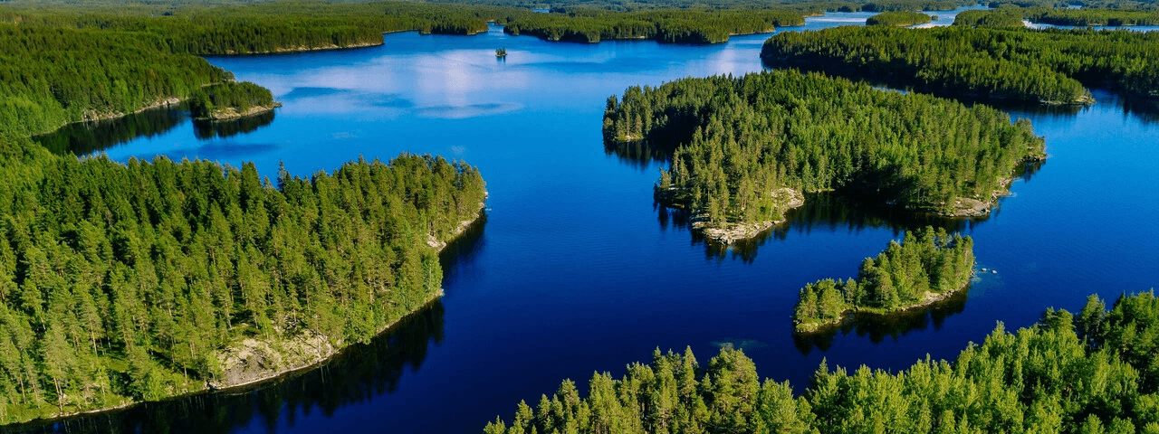 Drönarbild över en djupblå sjö med skogsbeklädda öar i och runt. 