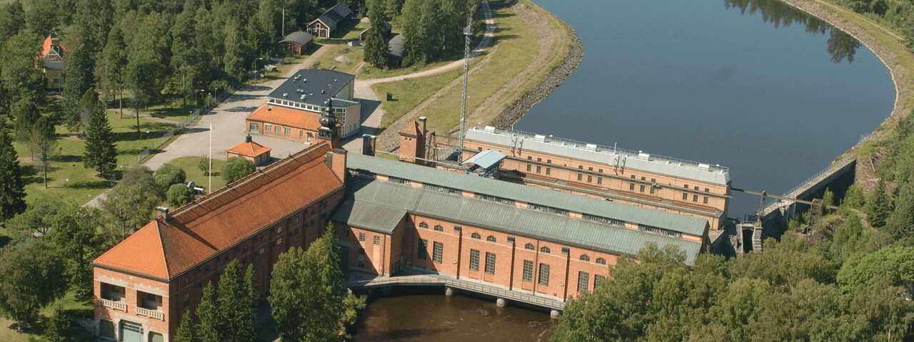 Vattenkraftverk på svensk landsbygd. Lugnt vatten rinner genom vattenturbinhuset.