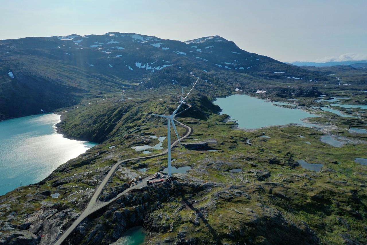 Vindkraftverk i en vacker, solig fjord i Sörfjord i Norge